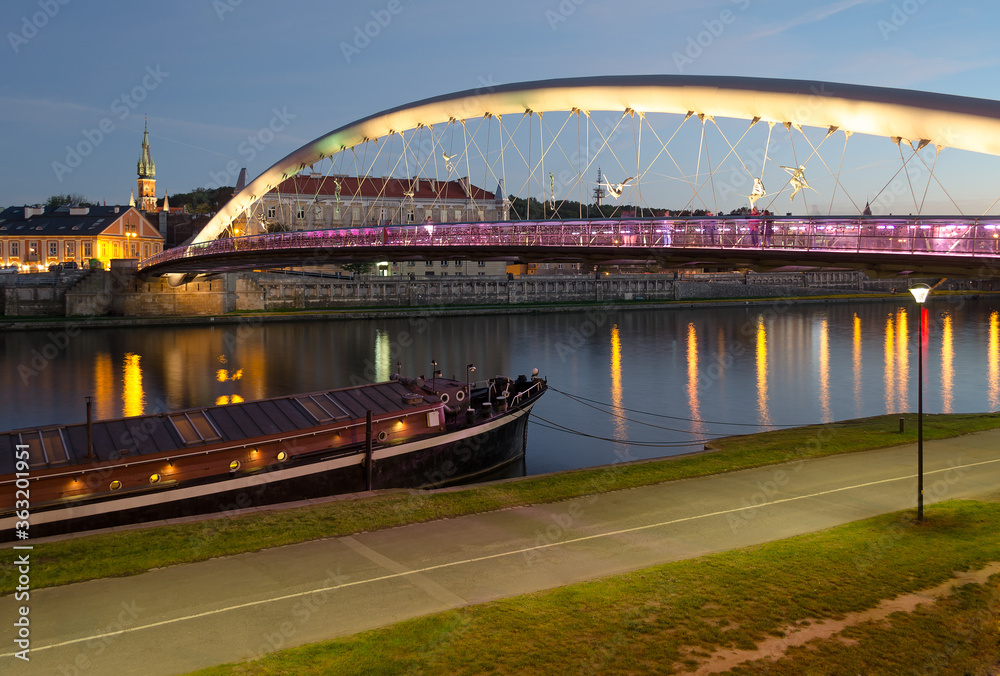 Obraz premium Father Bernatek Footbridge lit up at sunset in Krakow, Poland