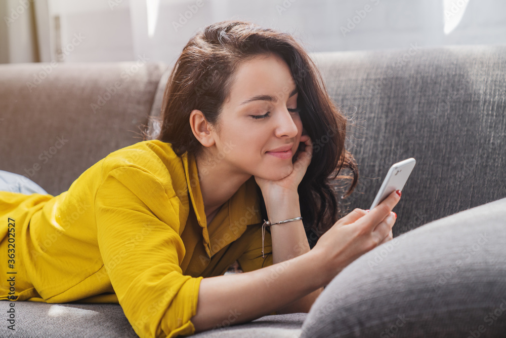 Relaxed smiling woman on the couch using smartphone and texting at home Relaxed smiling woman on the couch using smartphone and texting at home