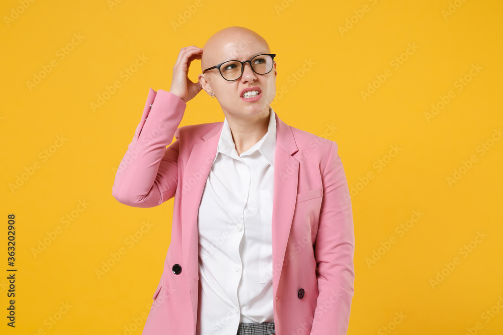 Preoccupied young bald business woman in white shirt pink jacket glasses isolated on yellow background. Achievement career wealth business concept. Mock up copy space. Put hand on head, looking aside.