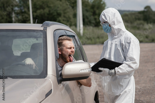 Doctor in protective virus suit taking swab from person driver to test for COVID-19 coronavirus infection © Parilov