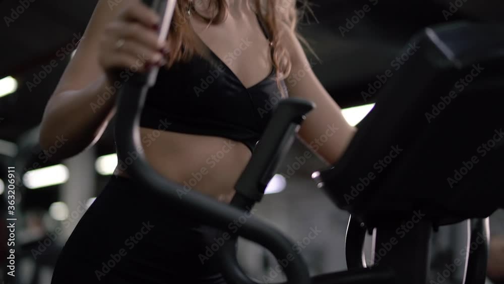 slim athletic girl in a black topic is engaged in cardio on an ellipsoid simulator slim athletic girl in a black topic is engaged in cardio on an ellipsoid simulator