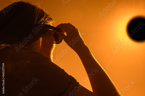 Woman is looking on solar eclipse through three sunglasses. Sun eclipse concept. photo