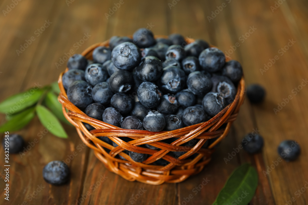 Tasty ripe blueberries in wicker bowl on wooden table Tasty ripe blueberries in wicker bowl on wooden table