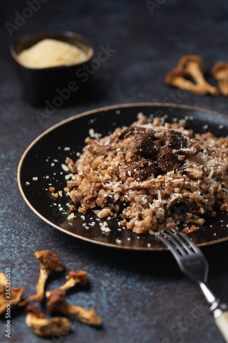 Cooked buckwheat with dried mushrooms on a plate sprinkled with Parmesan. Vegetarian food. Russian, Ukranian cuisine.