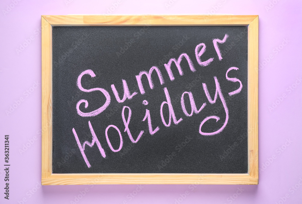 Chalkboard with phrase SUMMER HOLIDAYS on lilac background, top view. School's out Chalkboard with phrase SUMMER HOLIDAYS on lilac background, top view. School's out