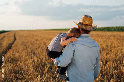 farmer and his grandson walking fields of wheat
