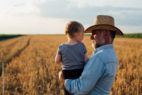 farmer and his grandson walking fields of wheat