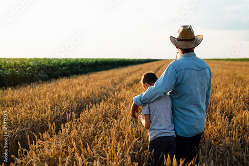 farmer and his son walking fields of wheat