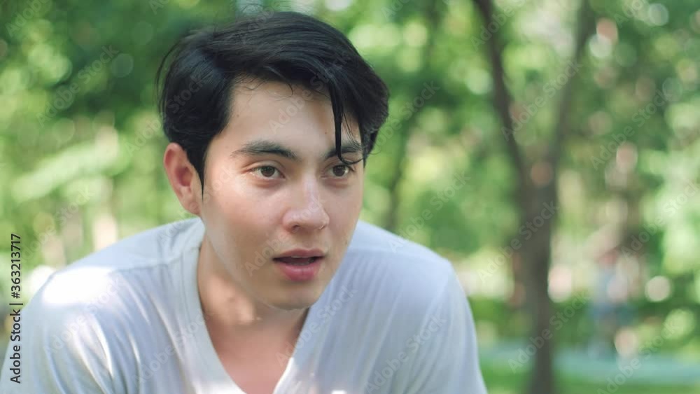 Sportive young Asian man running and bending over to catch breath, Man