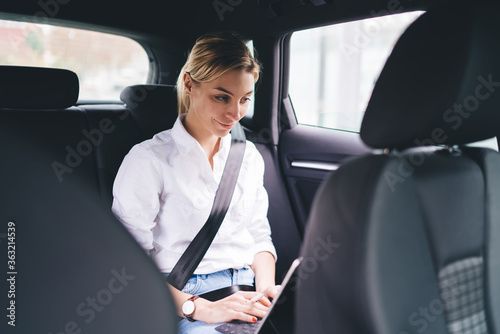 Cheerful woman smiling and thinking on back seat of car © BullRun