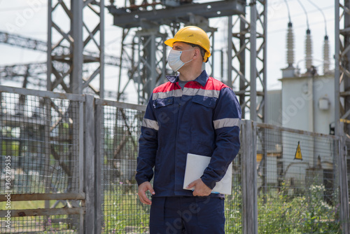 An electrical substation engineer inspects modern high-voltage equipment in a protective mask . Energy. Industry