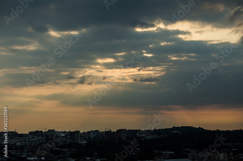 beautiful sunset with grey clouds on dramatic sky above cityscape silhouettes