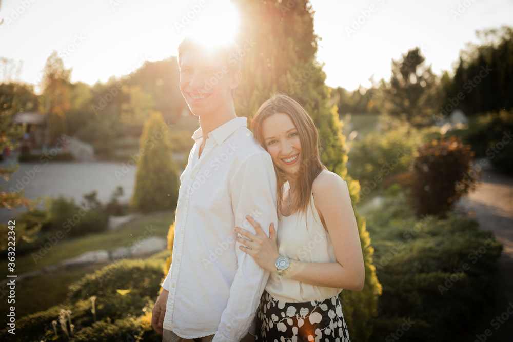 Fototapeta premium The young couple walking in the park. Couple hug. Man hug woman. Girl and boy on nature. On the sunset. Couple in love