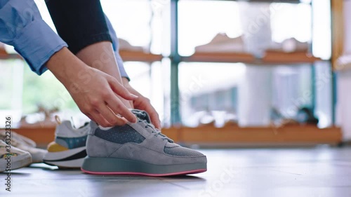In a luminous shoe shop a lady take a sit on the sofa and try to wear new pair of sport shoes