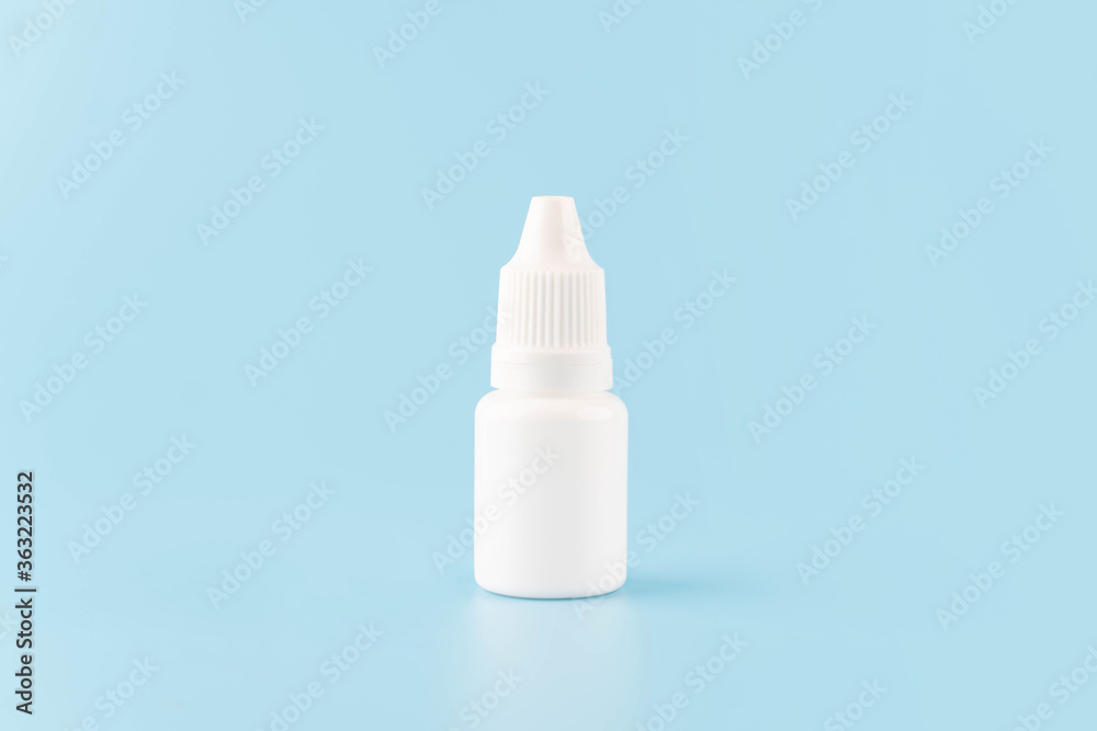 Eye drop or ear drop bottle on light blue background. Blank white plastic container for fluid. Pharmaceutical packaging product. Eye drop or ear drop bottle on light blue background. Blank white plastic container for fluid. Pharmaceutical packaging product.