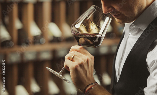 Male sommelier tasting red wine at cellar. photo