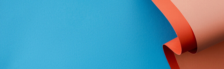 orange colorful paper swirl on blue background, panoramic shot