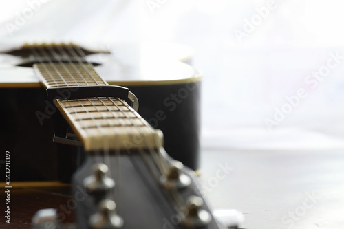 An acoustic guitar for an artist playing a stringed musical instrument on stage. Black guitar with a capo. Musical background.