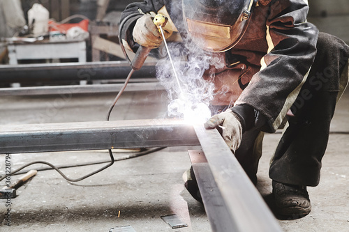 Male in face mask welds with welding photo