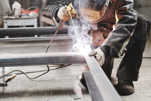 Male in face mask welds with welding
