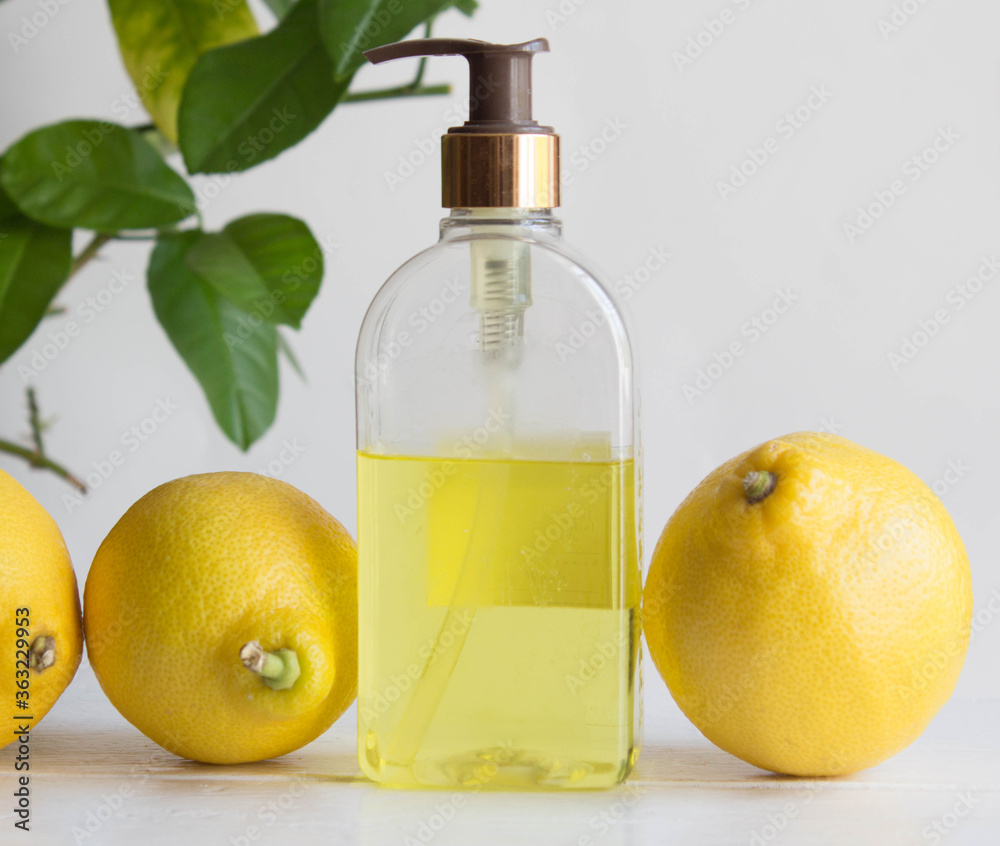 Cosmetic product with natural essential oil of lemon around with citrus leaves and lemon fruits. Lemon tree background.