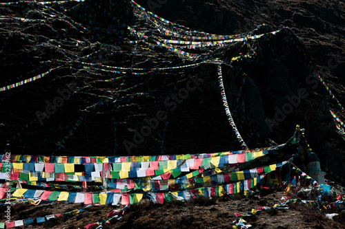 Colorful prayer flags at muktinath temple at mustang, Nepal with snow on summit. Blue sky sunny day and sun glare.  photo