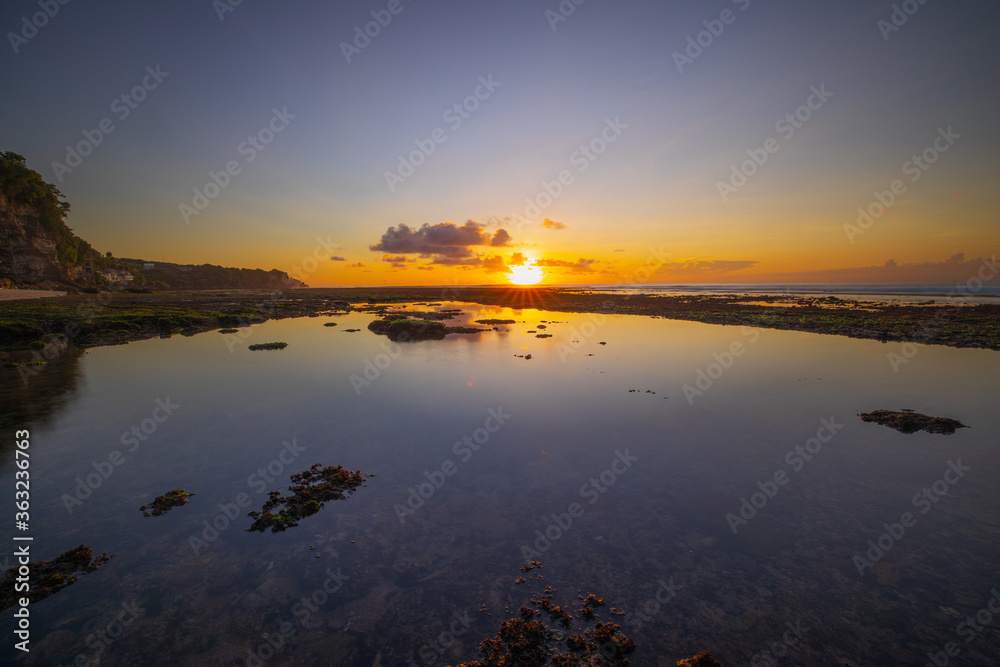 Seascape. Beach at sunset during low tide. Sunset golden hour. Bright sunlight reflection in water. Bingin beach, Bali, Indonesia