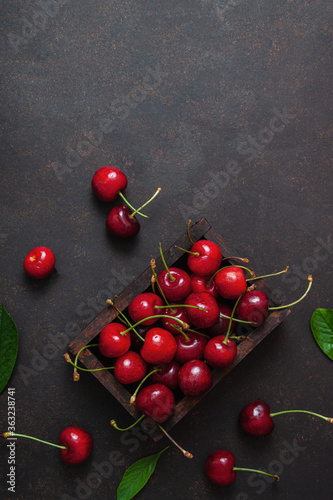 Cherry with leaf on plate and water dropsand on brown stone table