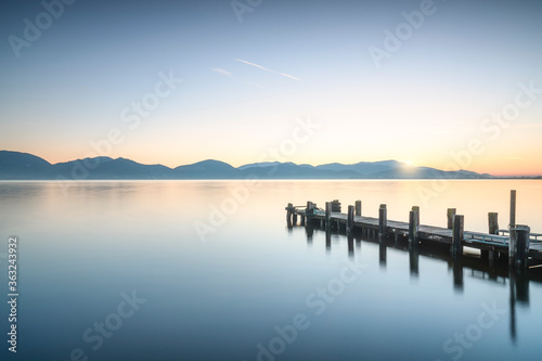 Wooden pier or jetty at sunrise and sky reflection on water. Versilia Tuscany  Italy