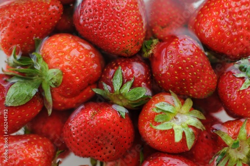 Close up background of home strawberry in bowl with water. Summer vitamins.