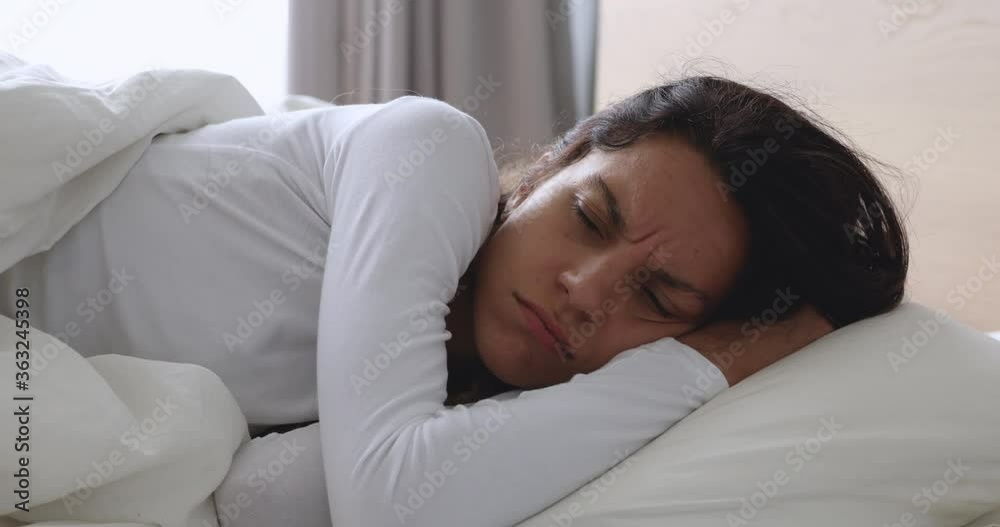 Frustrated upset young woman lying awake in bed alone trying to sleep suffer from insomnia or uncomfortable bad mattress, annoyed stressed lady insomniac feeling disturbed toss and turn in bedroom