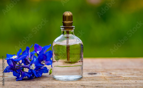 Perfume bottle with flowers on light background. Perfume bottle with tag and small flowers on the table.