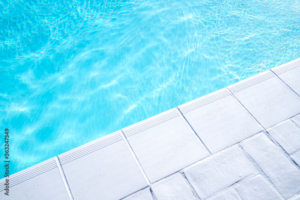 Empty swimming pool from a luxury house with white tiles around and clear transparent turquoise blue water. Real estate, property or hotel stylish pool