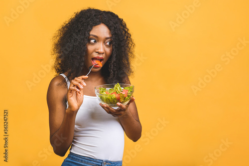 Healthy food concept. Close-up Of Beautiful African American black Woman Eating Salad isolated over yellow background.