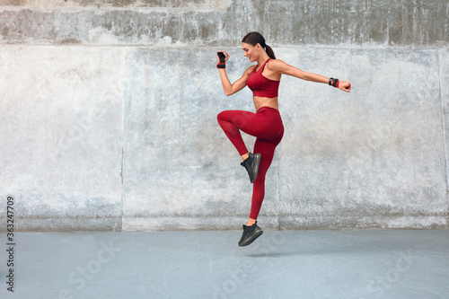 Woman. Fitness Workout With Jumping At Outdoor Stadium. Side View Of Sexy Girl With Strong Muscular Body Running On Spot. Fit Female In Fashion Sporty Outfit Training Outside.
