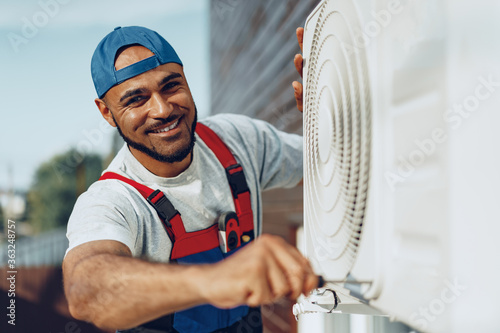 Young black man repairman checking an outside air conditioner unit photo