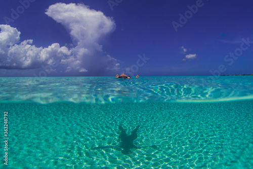 A young lady enjoys swimming in the perfectly blue Caribbean sea on Seven Mile Beach in Grand Cayman
