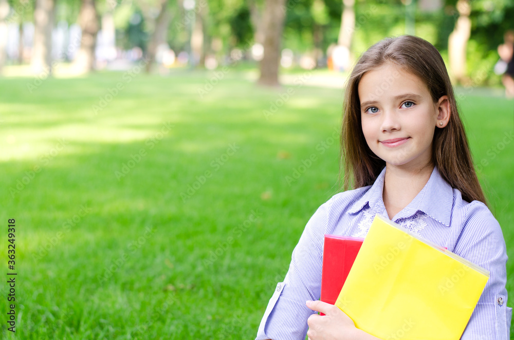 Back to school. Education concept. Cute smiling schoolgirl holding the books outdoor Back to school. Education concept. Cute smiling schoolgirl holding the books outdoor