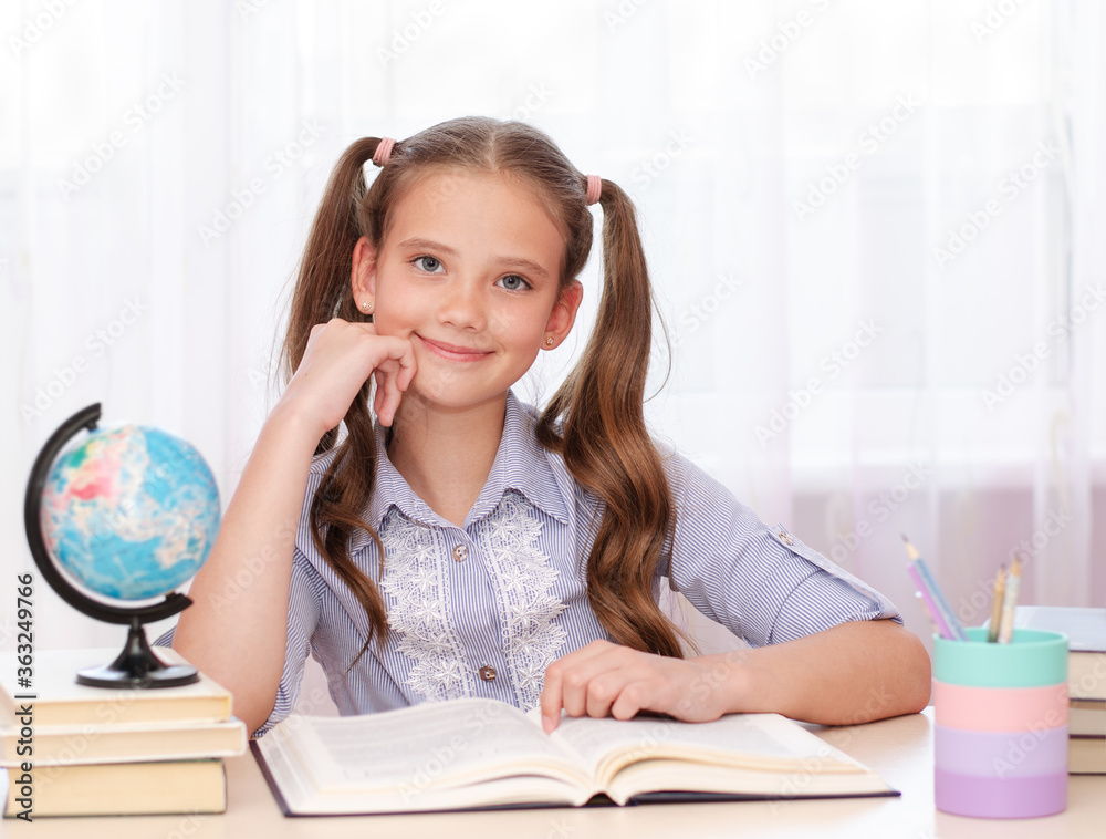 Education and school concept. Smiling happy child in glasses is sitting at the desk Education and school concept. Smiling happy child in glasses is sitting at the desk