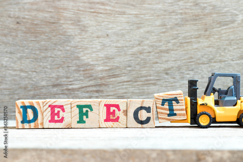 Toy forklift hold letter block T to complete word defect on wood background photo