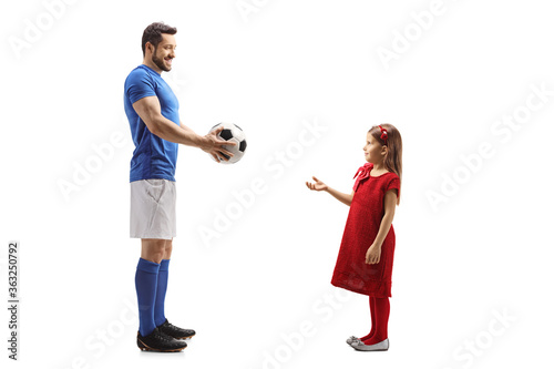 Football player giving a soccer ball to a little girl