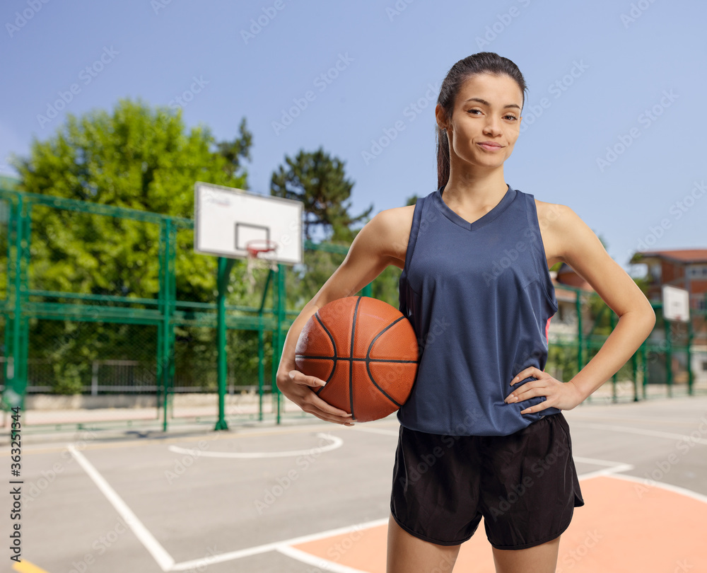 Young female with a basketball in an outdoor court Young female with a basketball in an outdoor court