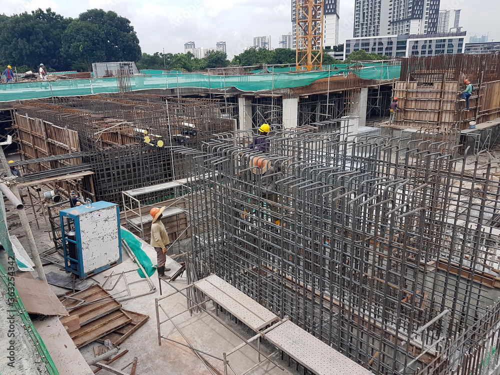 SEREMBAN, MALAYSIA -MARCH 29, 2020: Construction workers fabricating steel reinforcement bar at the construction site. They tied it together using the tiny wires. It is one of the steps in making of r