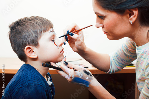 little cute child making facepaint on birthday party, zombie Apocalypse facepainting, halloween preparing concept, lifestyle people