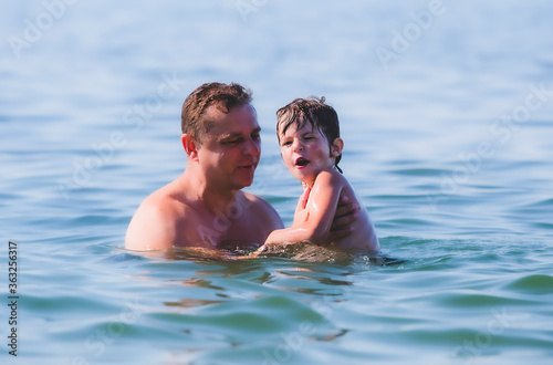 dad with his son are swimming in the sea.Sunny day. Mediterranean Sea.