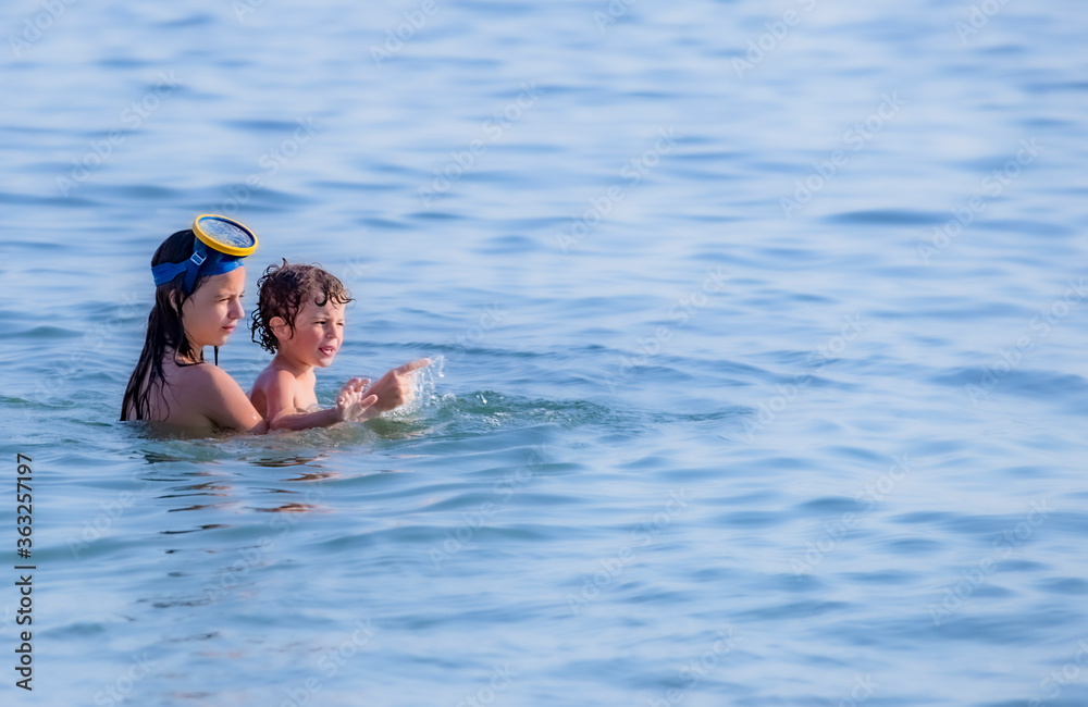 Brother and sister are swimming in the sea. Active summer vacation without gadgets. Travel destination. Copy space