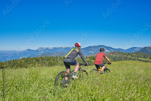 two men on mountain bike in a green field with blue sky