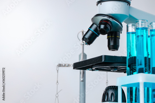 Close up of laboratory microscope with set of test tubes with blue liquid