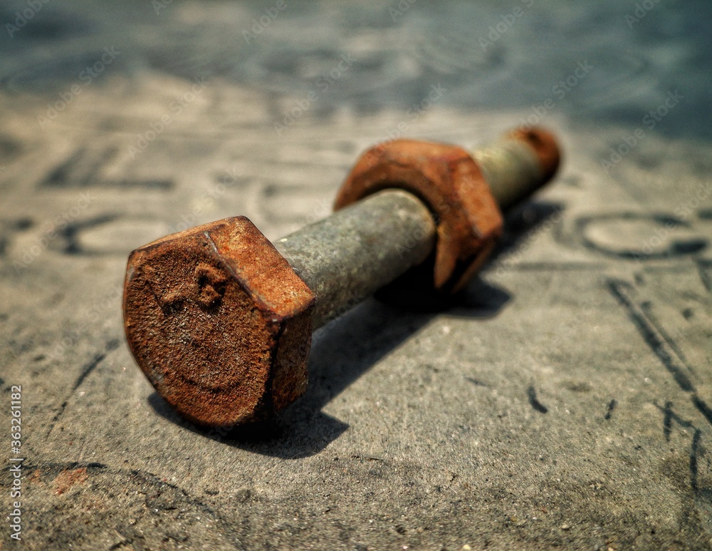 Macro shot of rustic and corroded isolated nut and bolt with dusty and construction background Macro shot of rustic and corroded isolated nut and bolt with dusty and construction background