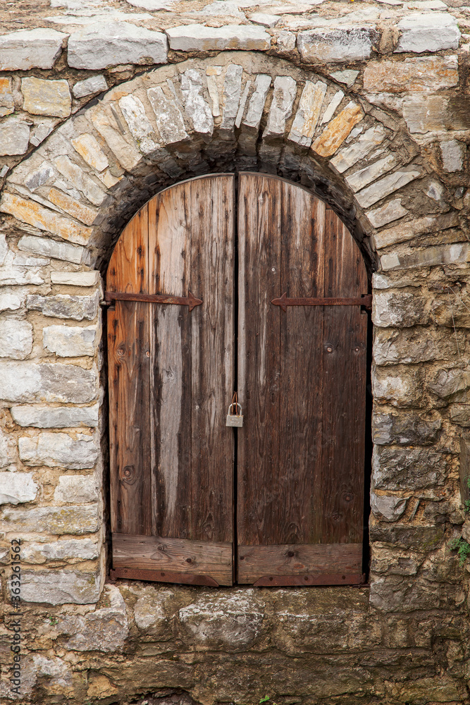 The gate of the medieval castle, the wooden gate doors in the stone walls. Ancient defensive structure, fort.